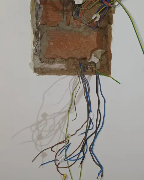 Mur ouvert pendant une rénovation, fils électriques prêts à être raccordés